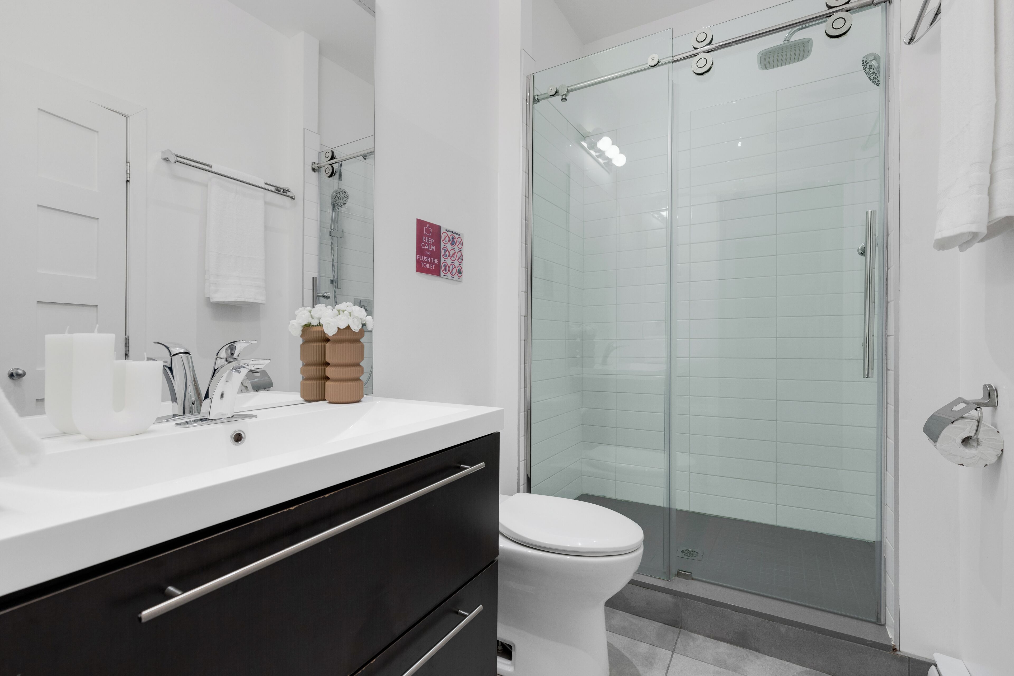 Un baño moderno con cabina de ducha de vidrio, un lavamanos blanco y un inodoro.