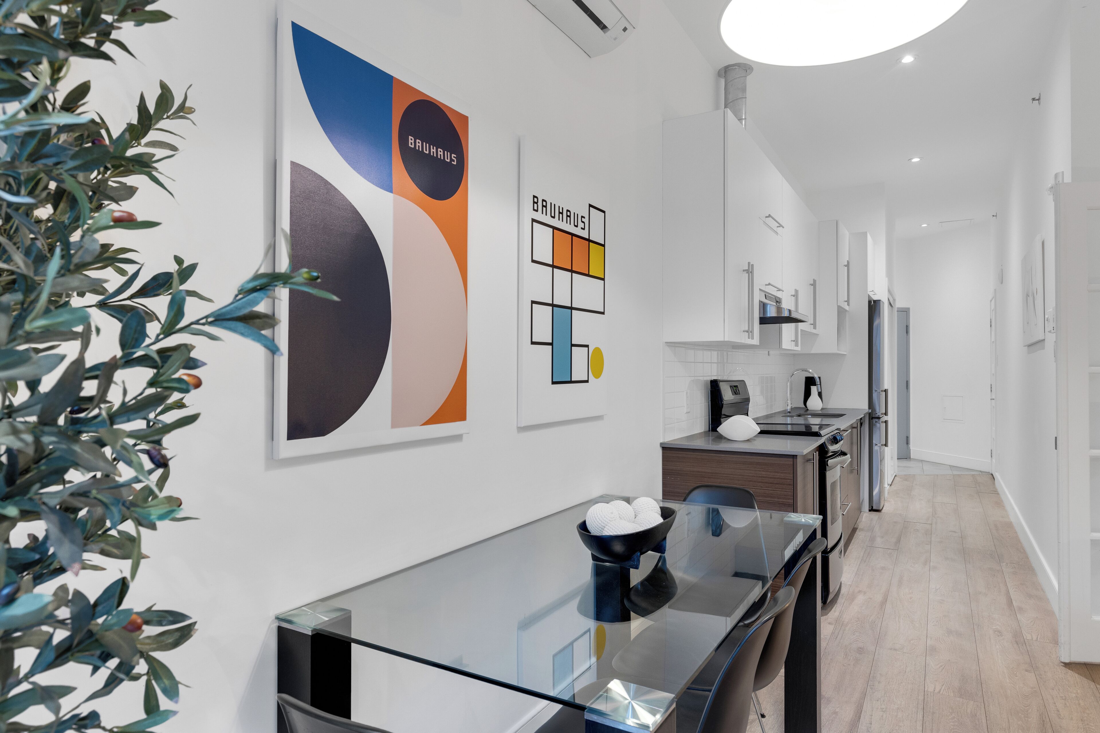 Une cuisine moderne avec des meubles blancs, un plan de travail noir et une table en verre.