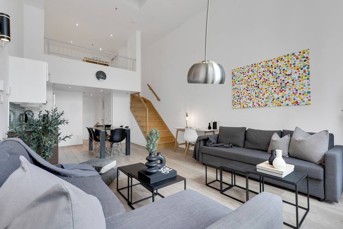 A modern living room with a grey sofa, a coffee table, and a staircase leading to an upper level.
