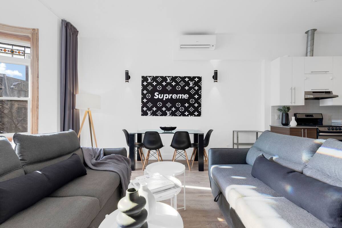 A modern living room with a sofa, a coffee table, and a dining area with chairs and a table.
