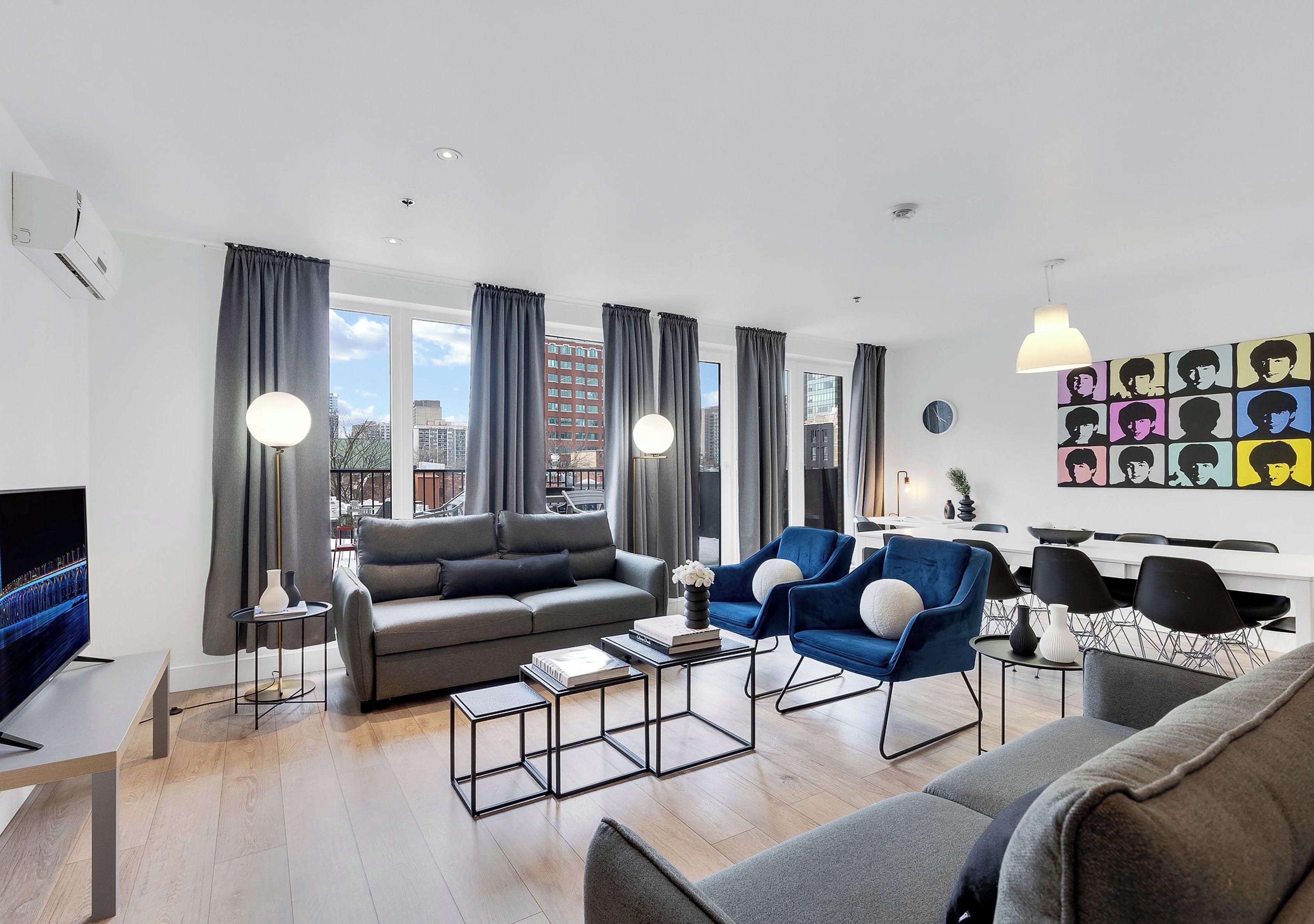 Una sala moderna con sofá, sillones, una mesa de centro y televisor.