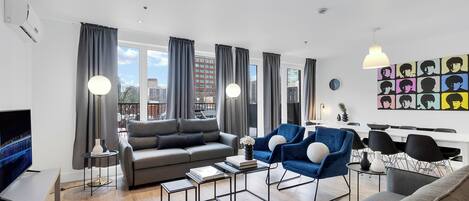 Una sala moderna con sofá, sillones, una mesa de centro y televisor.