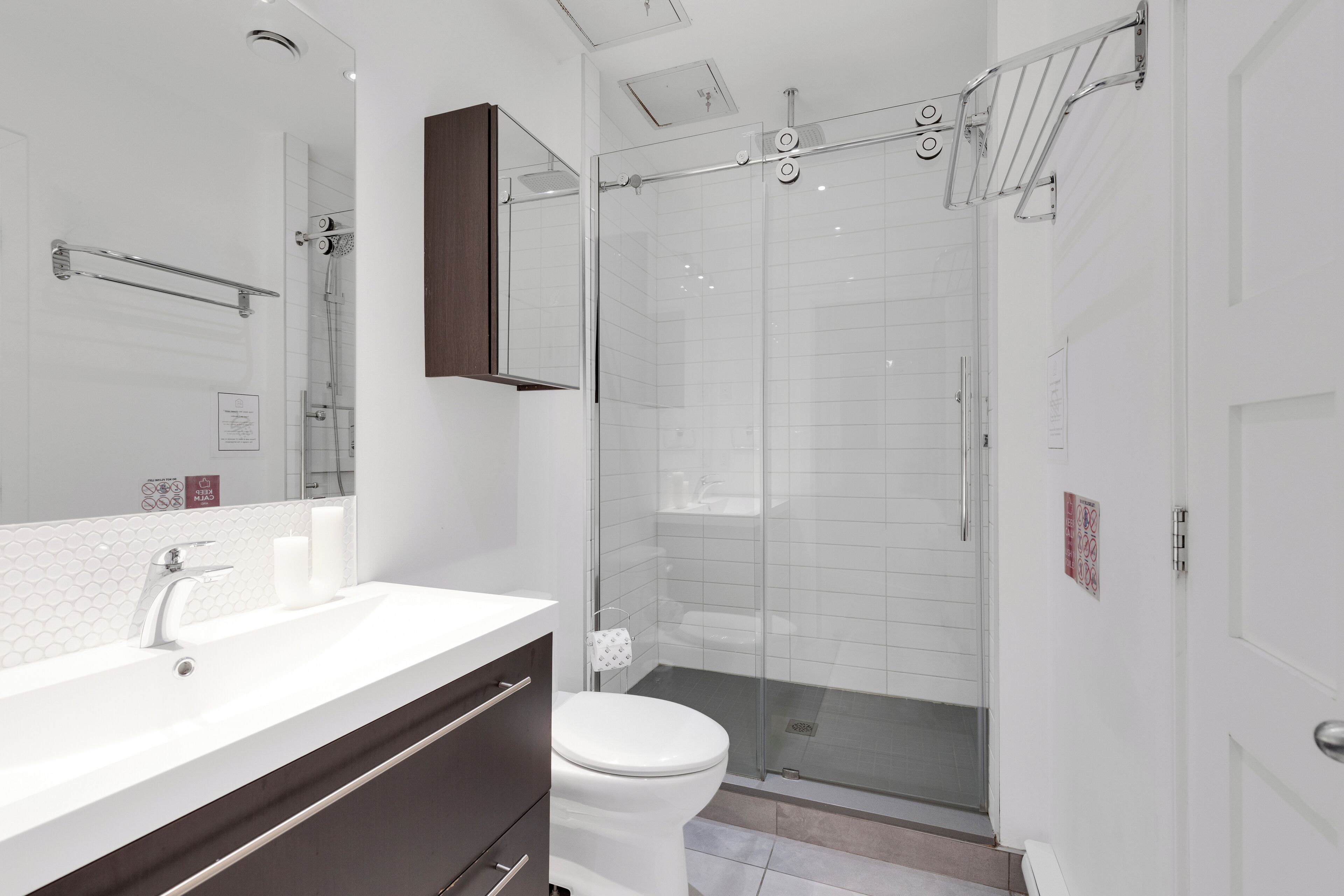A modern bathroom with a glass shower enclosure, a white sink with a vanity, and a toilet.