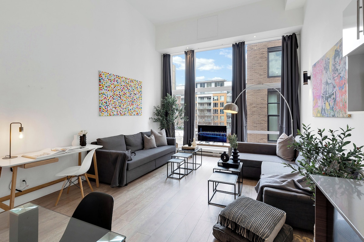 A modern living room with a sofa, coffee table, and a desk with a lamp.