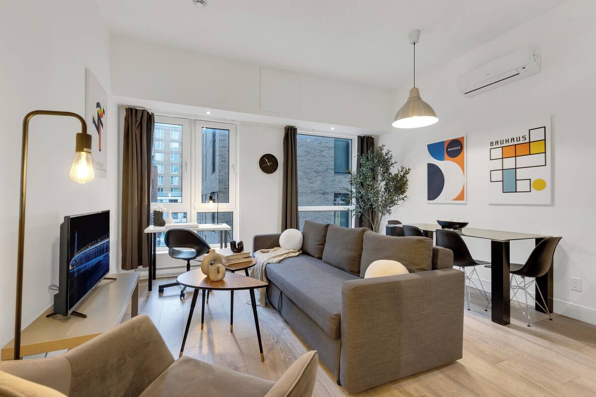 A modern living room with a sofa, coffee table, TV, and dining area.
