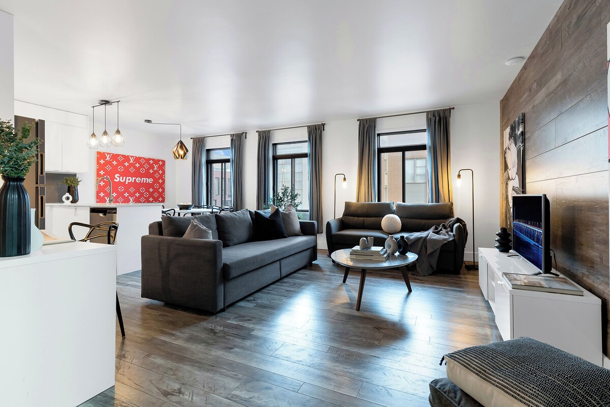 A modern living room with a grey sofa, a coffee table, and a TV on a stand.
