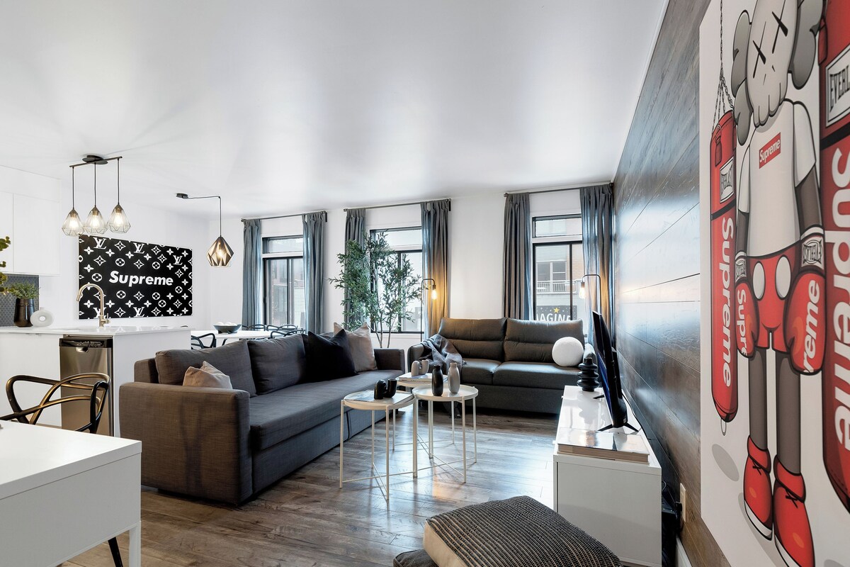 A modern living room with a sofa, a dining area, and a kitchen.