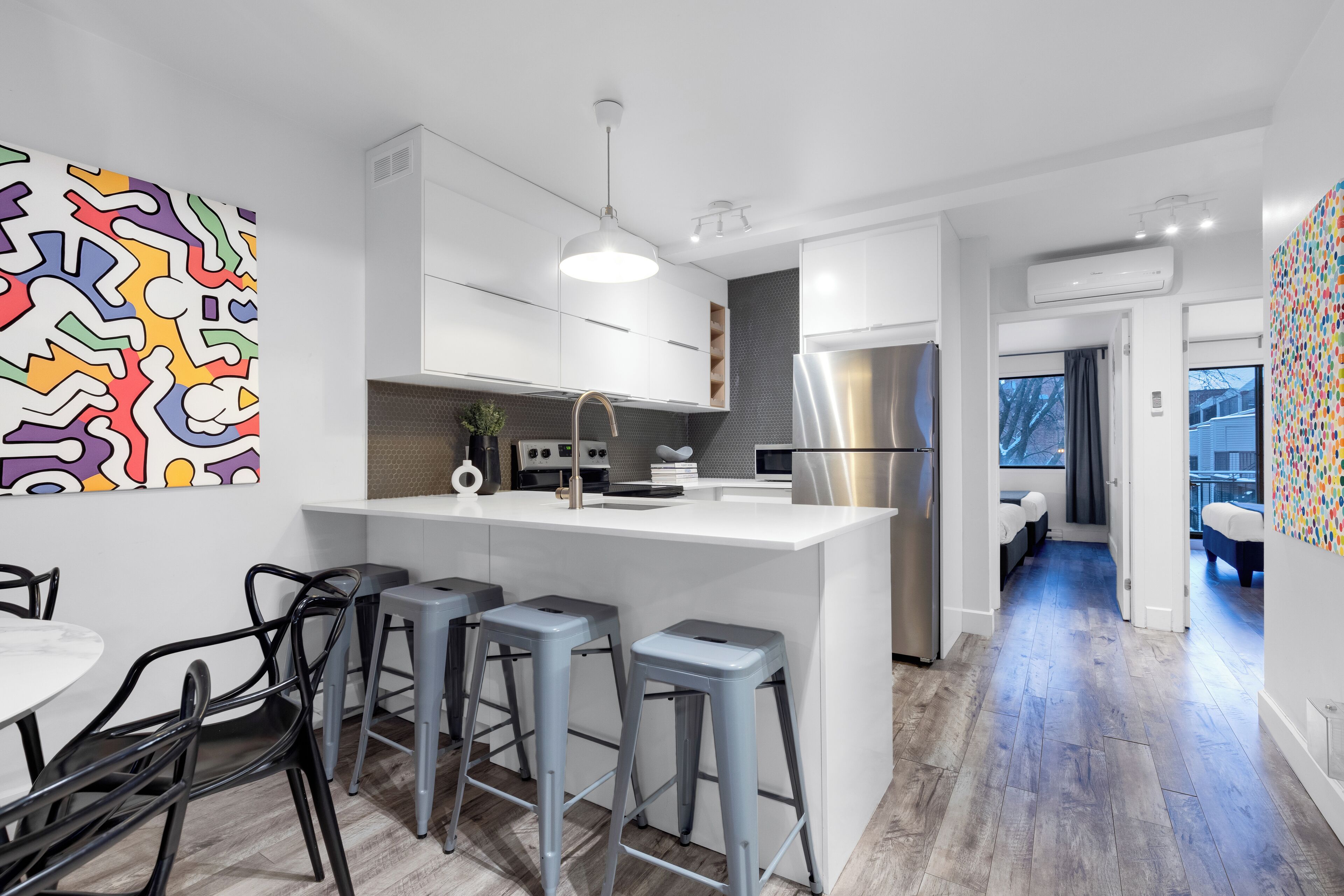 A modern kitchen with white cabinetry, a stainless steel refrigerator, and a central island with bar stools.