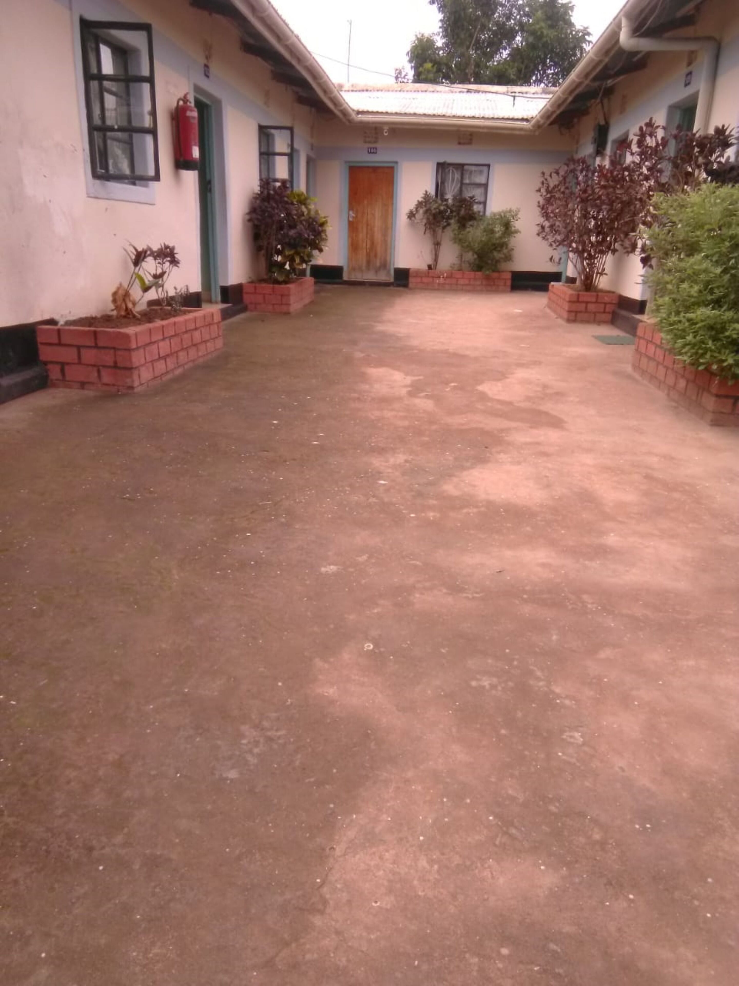 A building with a central courtyard, brick planters with plants, and a fire extinguisher mounted on the wall.