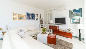 A modern living room with a sofa, coffee table, TV, and artwork on the walls. - Villa Vista Old Town (Konavle)