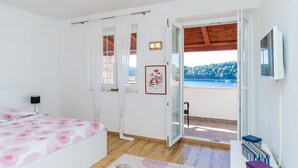 A bedroom with a bed, a window with curtains, a framed picture, and a view of a balcony with a pool. - Villa Vista Old Town (Konavle)