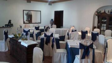 A banquet hall with round tables, chairs with blue sashes, and a large mirror on the wall.
