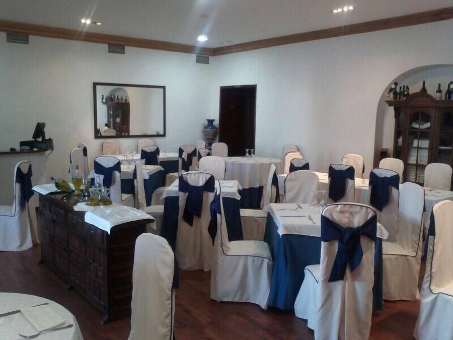 A banquet hall with round tables, chairs with blue sashes, and a large mirror on the wall.