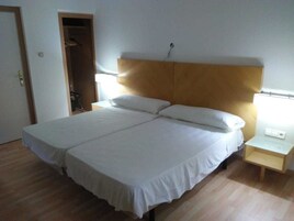 Una cama doble con ropa blanca, dos mesitas de noche con lámparas y un cabecero de madera.
