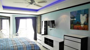 A modern bedroom with a bed, a TV, and a painting. - Sea View 1-bed at Jomtien Beach - Sleeps 2 (Pattaya)