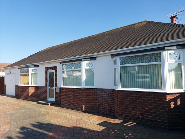 A two-story house with a brick facade, white-framed windows, and a tiled roof. - The Hermitage Private Detached Bungalow (Rhyl)