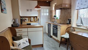 Kompakti keittiö, jossa on ruokailutila, puuhuonekalut ja ikkuna, josta on näkymä.
