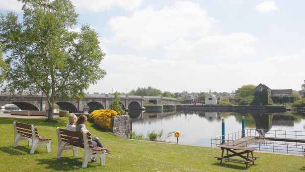A riverside park with benches, a picnic table, and a stone bridge in the background. - Apartment Sleeps 7 With Mezzanine (Birr)