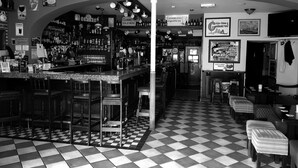 A bar area with a checkered floor, bar stools, and shelves stocked with bottles. - Apartment Sleeps 7 With Mezzanine (Birr)