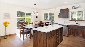A modern kitchen with wooden cabinets, a central island, and a dining area with chairs. - Hawkeye Ridge -- Ev 6189 3 Bedroom Condo by RedAwning (Estes Park)