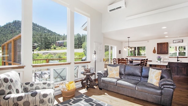 A spacious living room with a large gray sofa, patterned armchairs, and a dining area with a wooden table and chairs. - Hawkeye Ridge -- Ev 6189 3 Bedroom Condo by RedAwning (Estes Park)