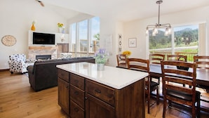 A spacious living room with a large island, a dining area with wooden chairs, a fireplace, and a television. - Hawkeye Ridge -- Ev 6189 3 Bedroom Condo by RedAwning (Estes Park)