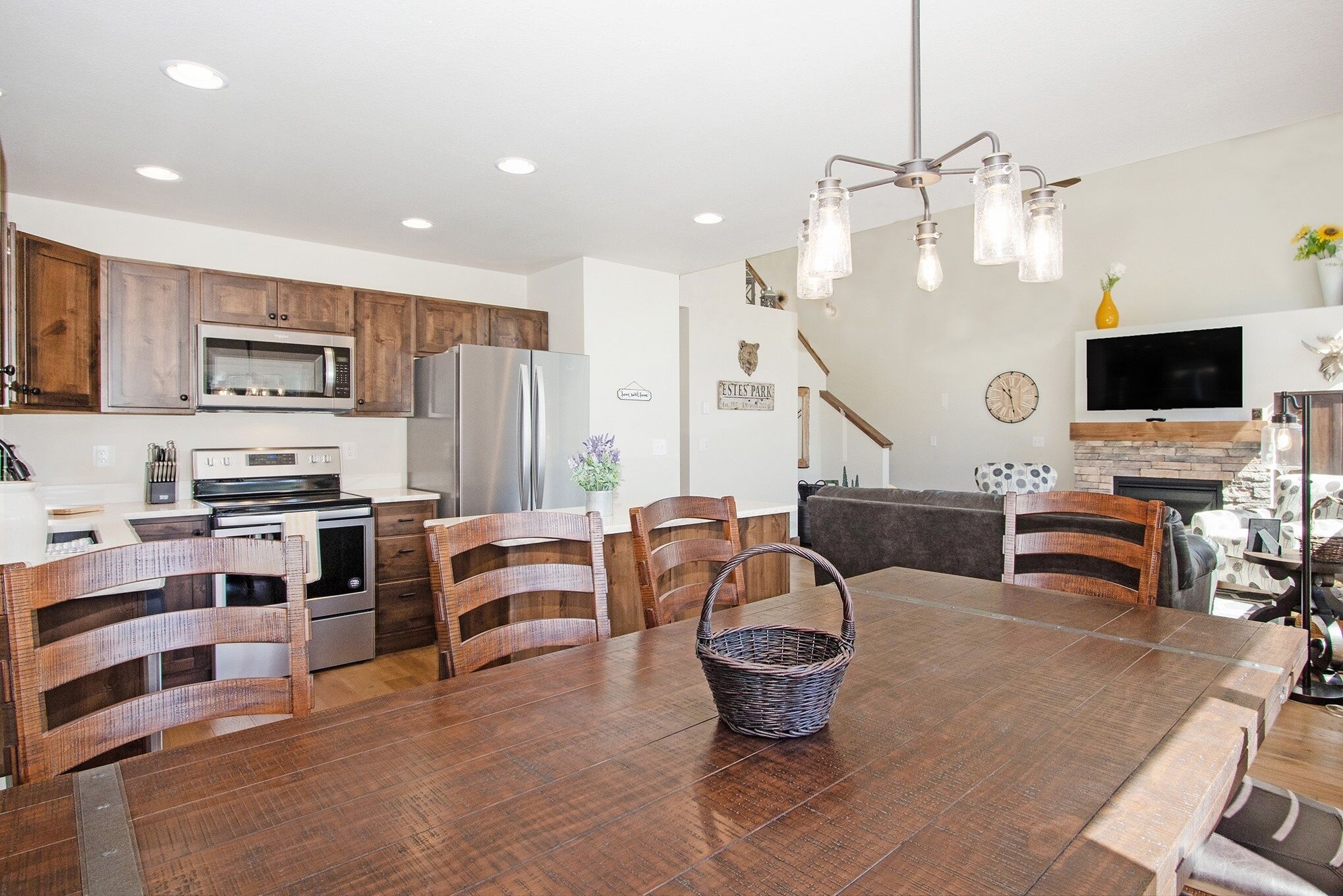 A modern kitchen with wooden cabinets, stainless steel appliances, and a dining area with a wooden table and chairs.