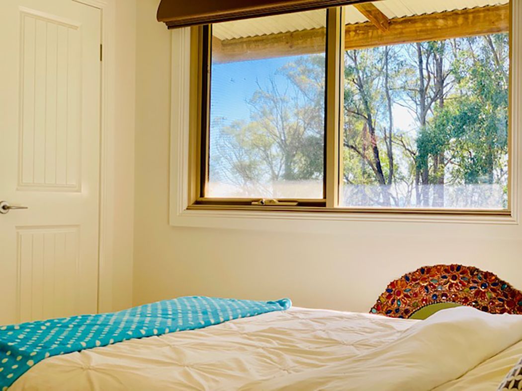 A bedroom with a bed, a window with a view of trees, and a white door.