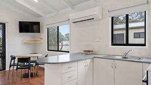 A modern kitchen with a built-in stove, a sink, and a window overlooking the street. - Discovery Parks - Mildura (Buronga)
