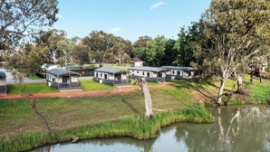 A lakeside campground with multiple cabins, a grassy area, and a pond. - Discovery Parks - Mildura (Buronga)