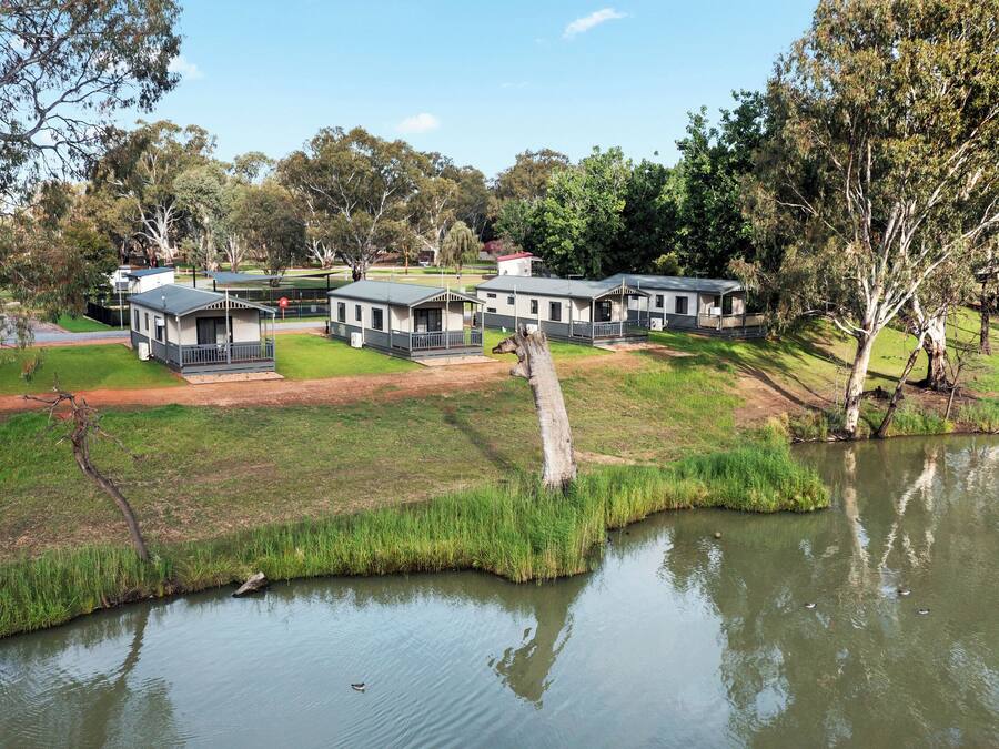 A lakeside campground with multiple cabins, a grassy area, and a pond.