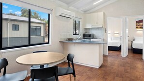 A compact kitchen with a dining area, a microwave, and a sink. There is a window providing a view of the outside. - Discovery Parks - Mildura (Buronga)