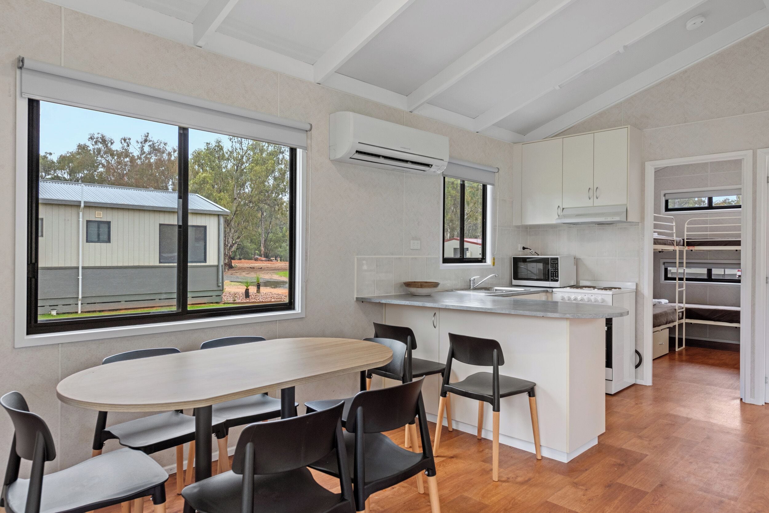 A modern kitchen with a central island, white cabinetry, and a large window overlooking a residential area.