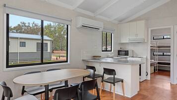 A modern kitchen with a central island, white cabinetry, and a large window overlooking a residential area.