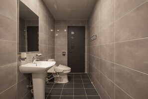 A modern bathroom with a white sink, toilet, and dark tiled floor. - Yellow 8 Hotel (Goyang)