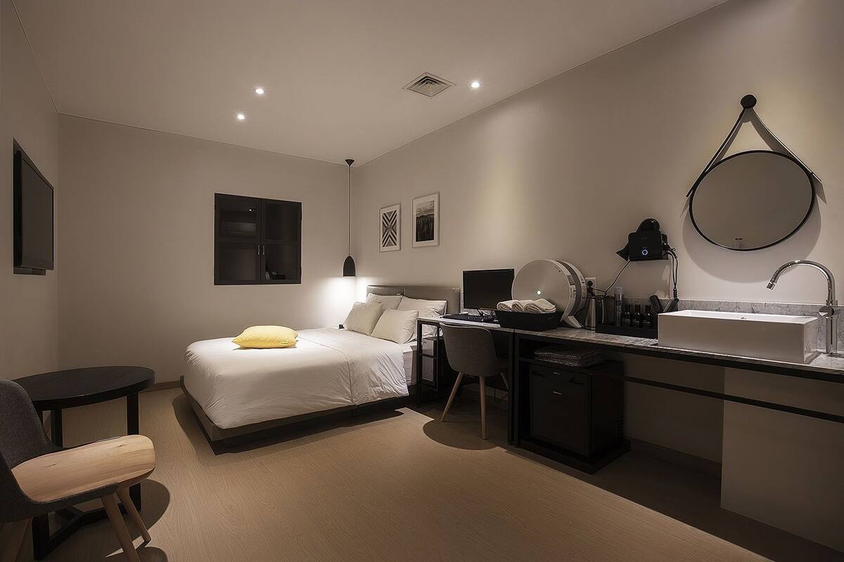 A modern hotel room with a bed, desk, and bathroom.