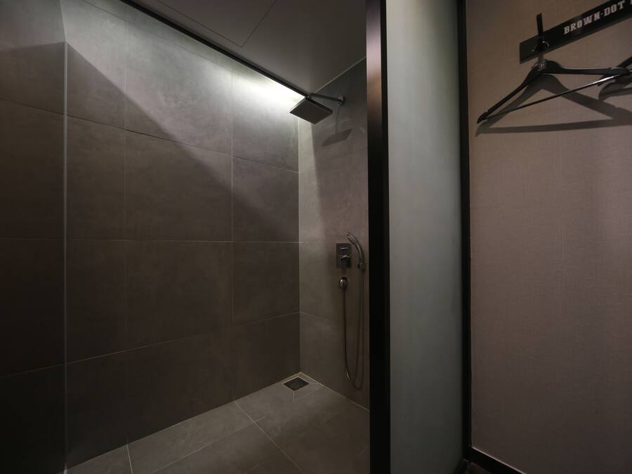 Un espacio de ducha moderno con un cabezal de ducha empotrado y un perchero.