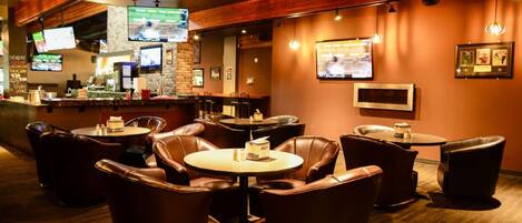 A restaurant with leather seating, a bar area, and multiple televisions displaying sports.