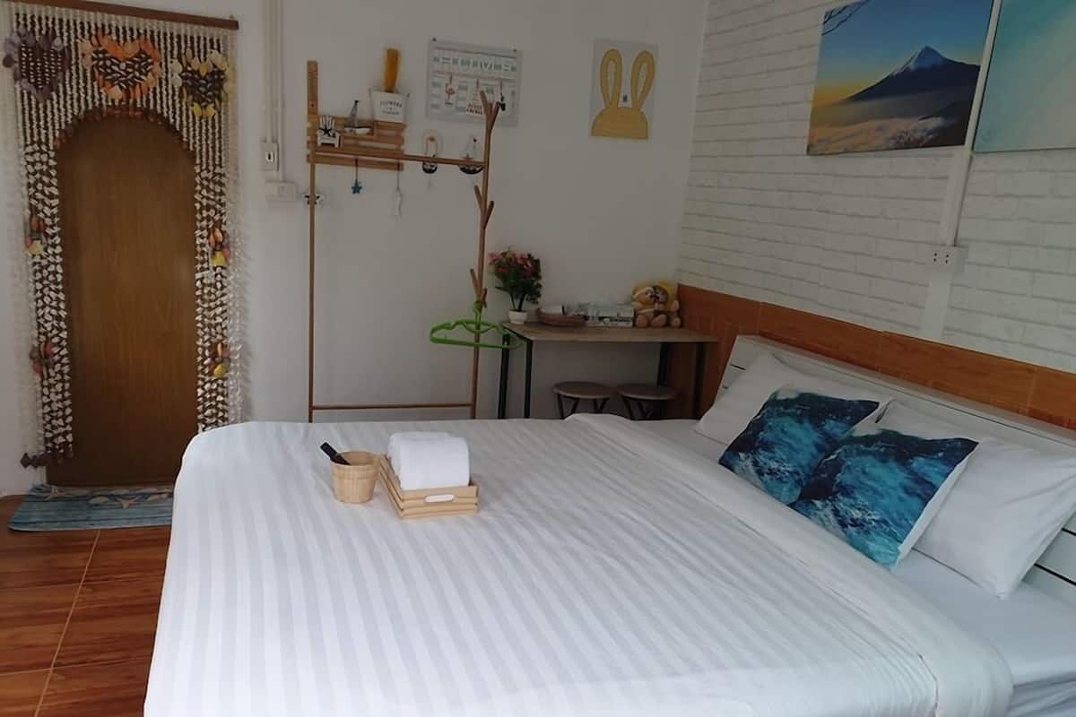 Uma cama bem arrumada com colcha listrada, cabeceira de madeira e dois travesseiros com padrão azul.