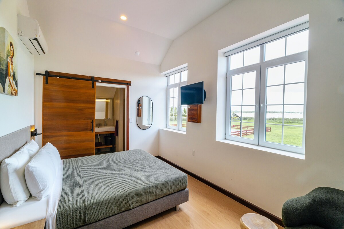 Un dormitorio con cama, armario correderas, ventana grande con vistas y televisor montado.