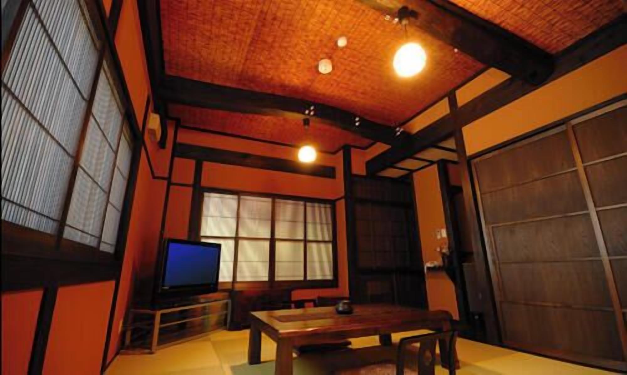 A traditional Japanese room with tatami flooring, a low wooden table, a television, and sliding doors.