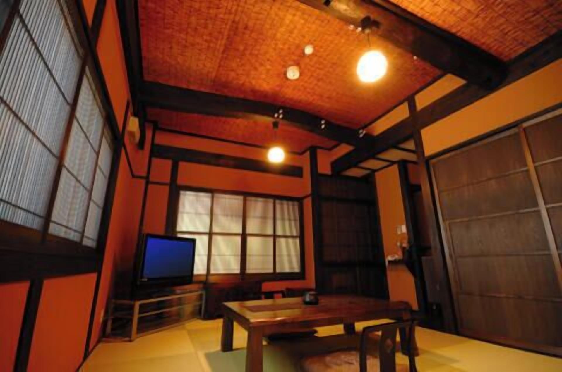 A traditional Japanese room with tatami flooring, a low table, a television, and sliding doors.