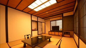 Una habitación japonesa tradicional con suelo de tatami, una mesa baja y puertas correderas.