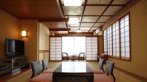 Una habitación japonesa tradicional con suelo de tatami, una mesita baja y puertas correderas.