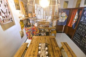 A room with a wooden table, shelves with various items, and a chalkboard with writing. - I am waiting for you in Guilin Youth Hostel (Liangjiang Sihu East-West Alley) (Guilin)