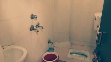 A small bathroom with a toilet, bidet, and a bucket.