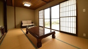 A traditional Japanese room with tatami flooring, a low wooden table, a sofa, and large shoji screens. - Chouja Yashiki (Nanyo)