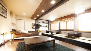 A modern living room with a sofa, a table, and a TV mounted on the wall. - Chouja Yashiki (Nanyo)