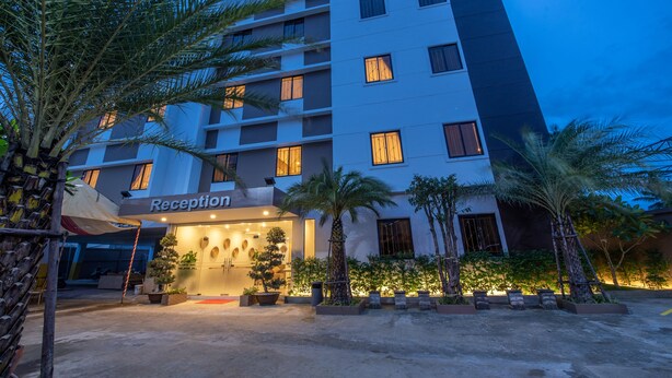 A multi-story hotel with a reception area, palm trees, and a well-lit entrance. - Double S Hotel (Battambang)