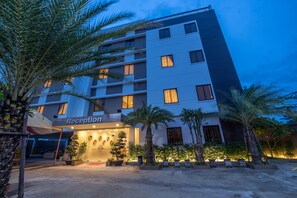 A multi-story hotel with a reception area, palm trees, and a well-lit entrance. - Double S Hotel (Battambang)